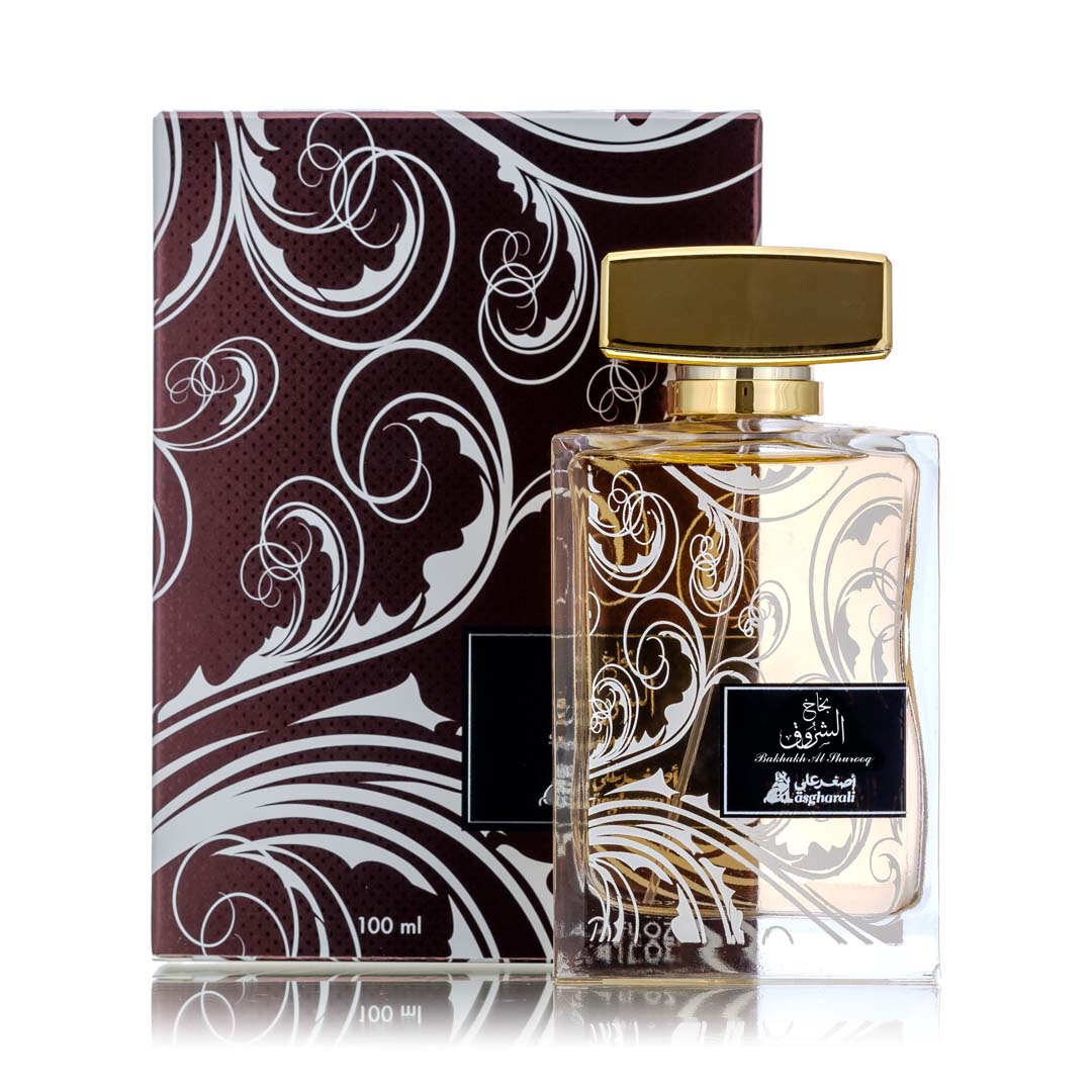 “Bakhakh Al Shurooq perfume bottle displayed alongside its matching maroon box with floral swirls and black label.”