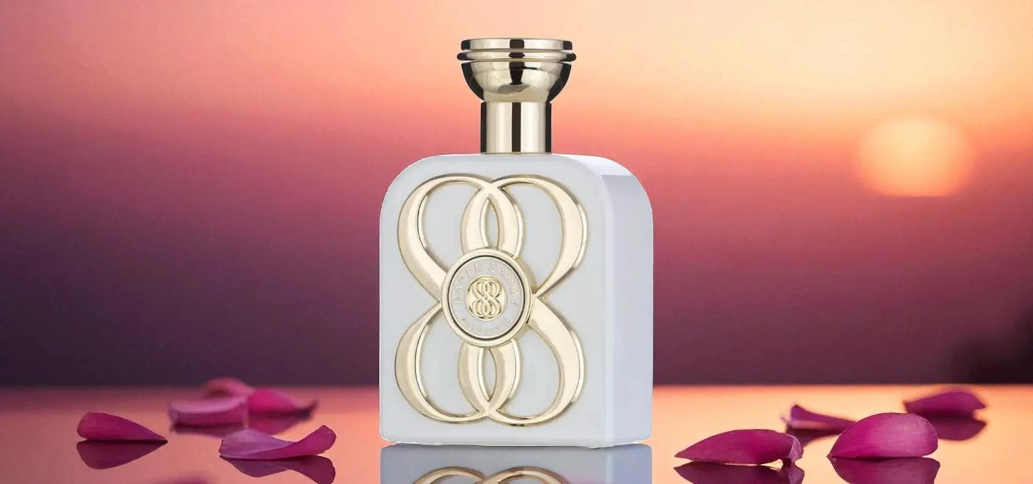 Perfume bottle with gold accents on a reflective surface with pink petals, against a blurred background.